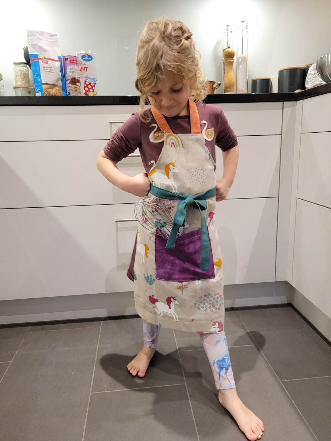 Mädchen in Küche mit textiler Kochschürze